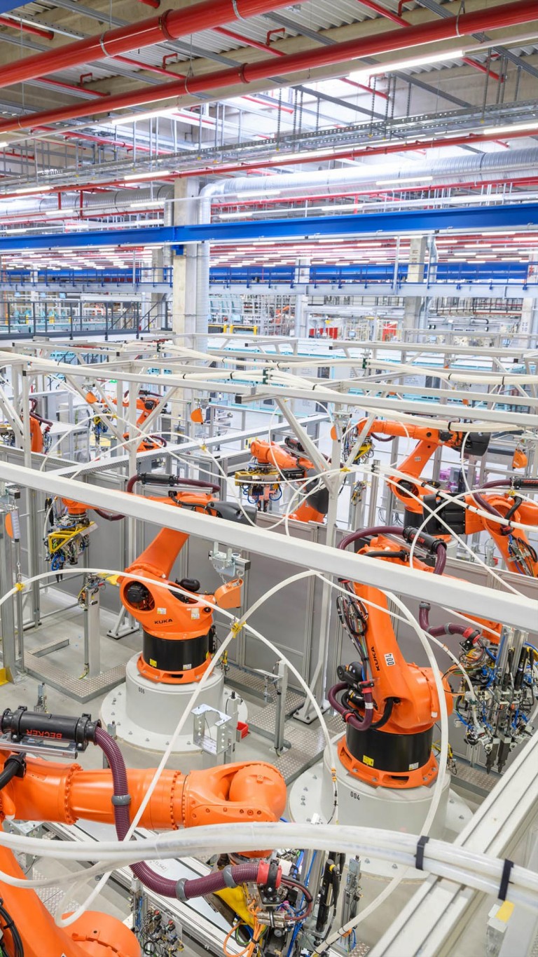 Overhead view of the specialised, orange-coloured robots housed within the main assembly building of Plant Leipzig.